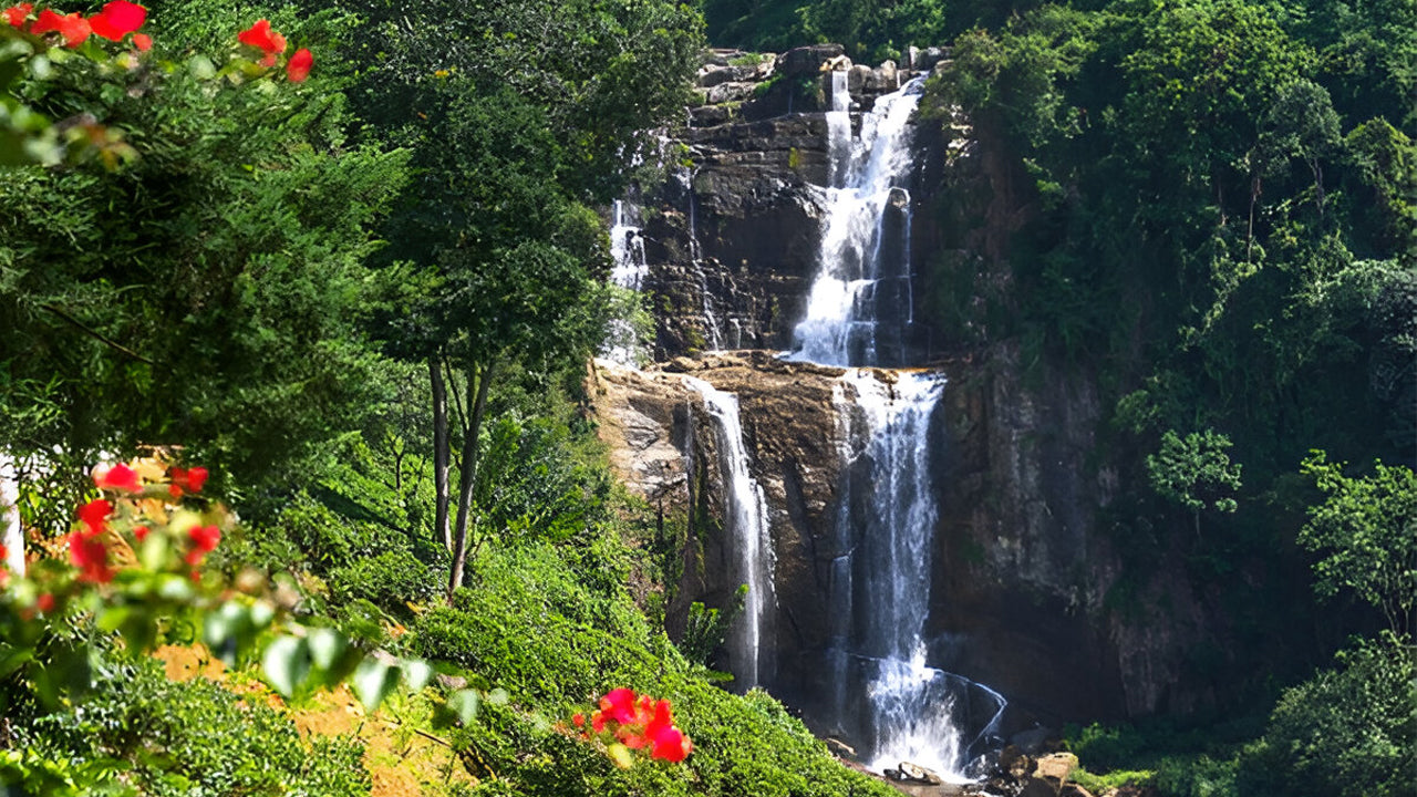 Waterfall surrounded by lush greenery and red flowers