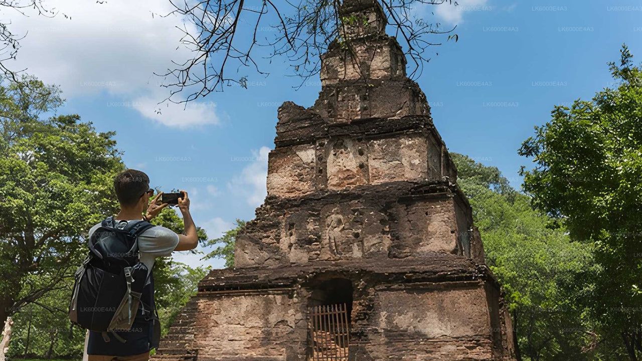 Person taking a photo of an ancient stone temple with trees and blue sky in the background